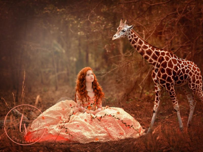 Fantasy portrait of a child in a ball gown next to giraffe