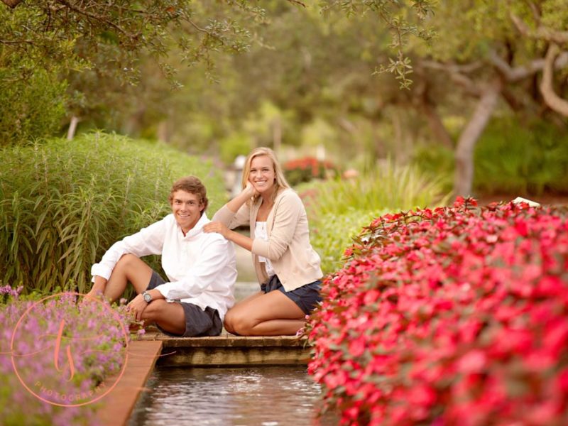 engaged couple man and woman posing among flowers and small pond