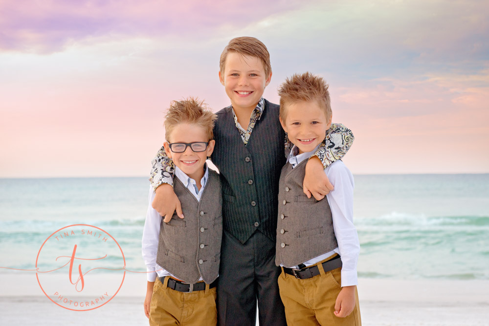 three brothers hugging on the beach at sunrise