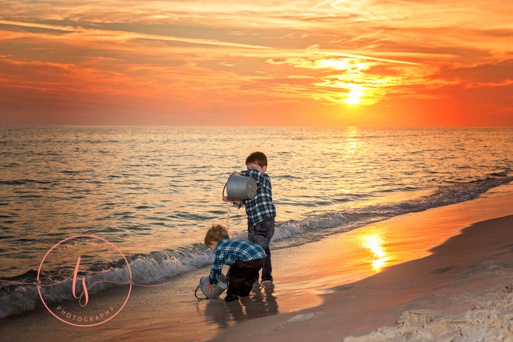 brothers playing in the water on the beach in destin at sunset