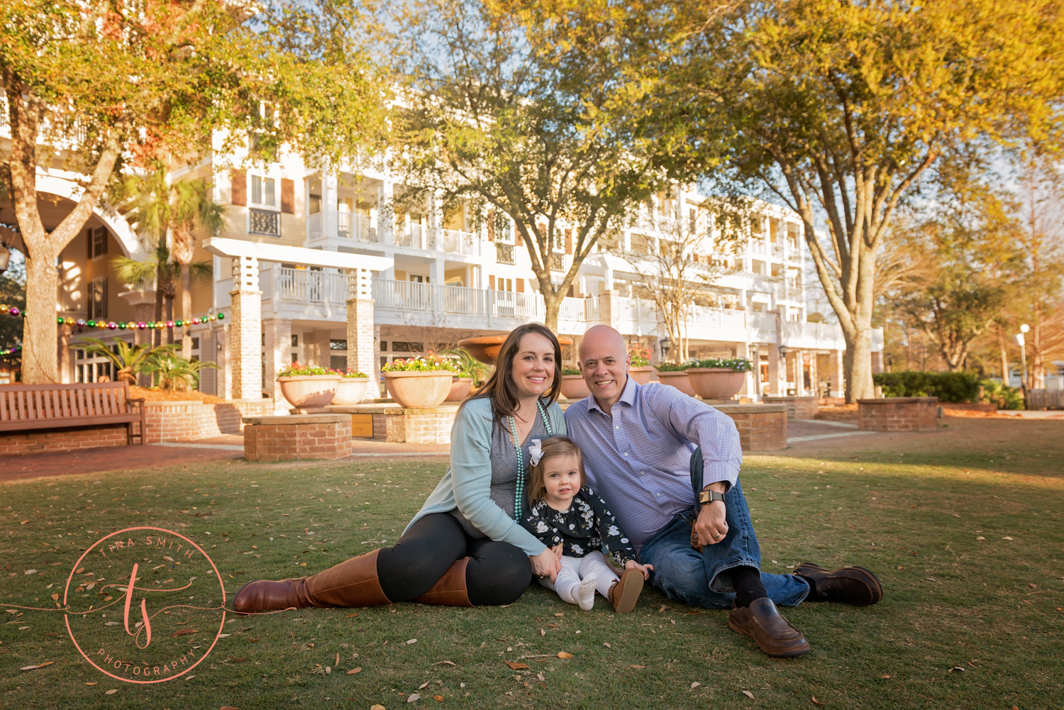 family sitting on lawn baytowne wharf smiling for photographer