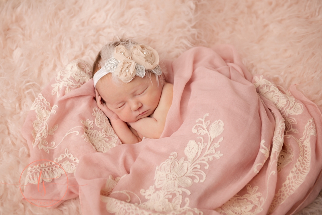 newborn baby on beige fur with pink flowered wrap posed for pictures