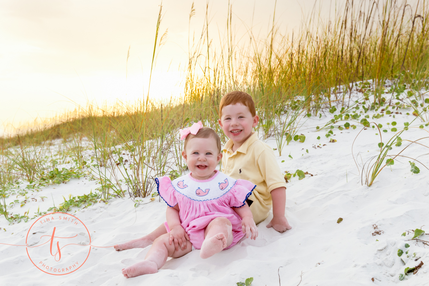 children sitting on beach smiling for portraits