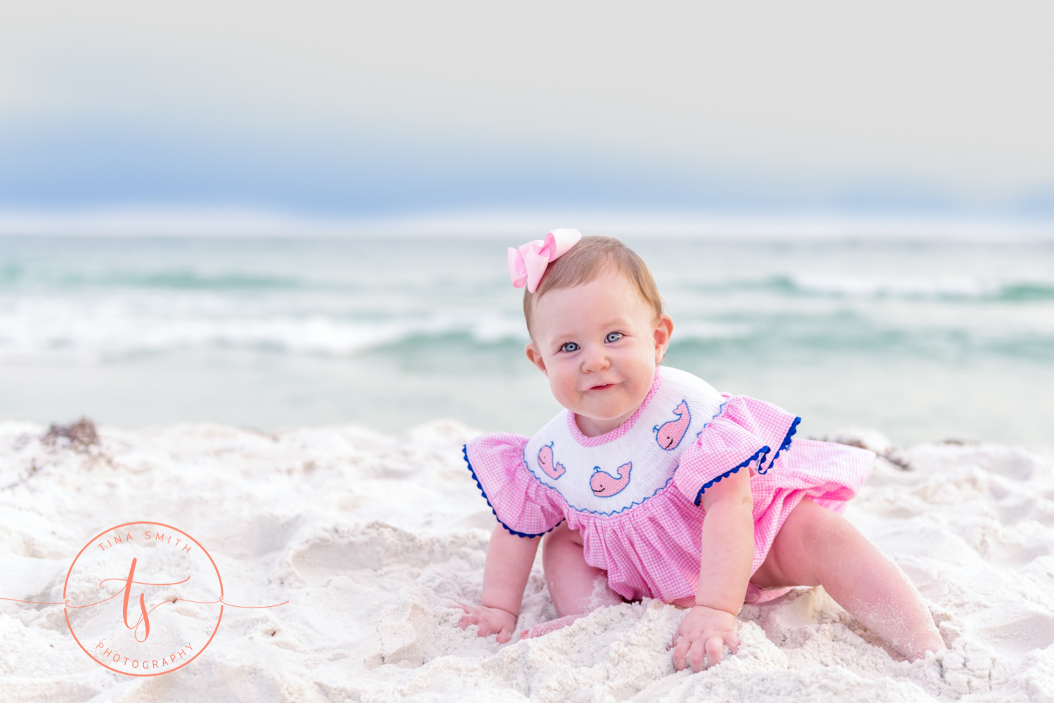 baby girl crawling on beach in dests dressed in pink dress