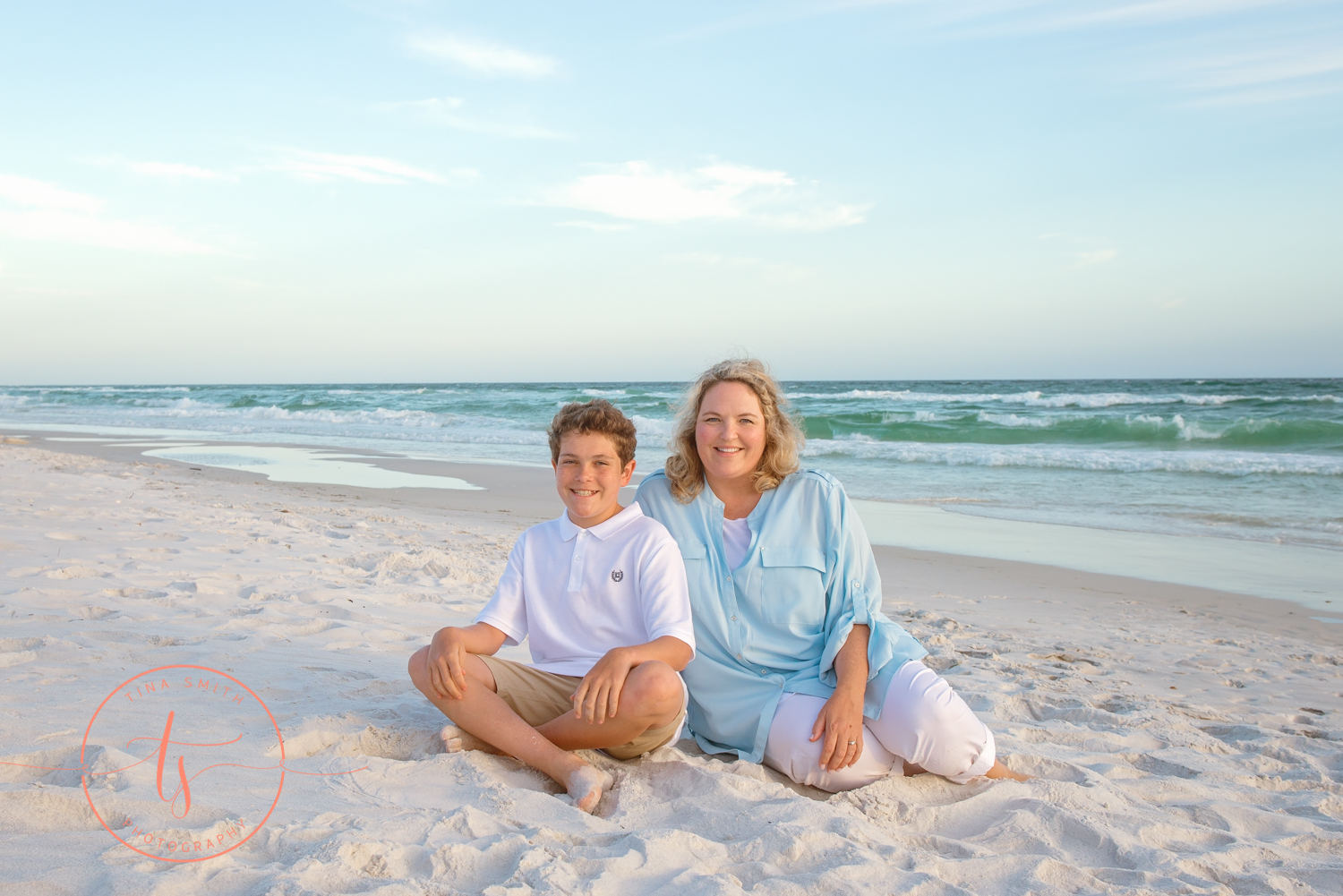 mom and son sitting on watersound beach smiling for photographer