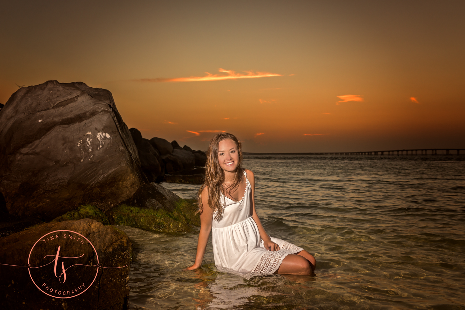 girl in white dress sitting in water at beach in destin