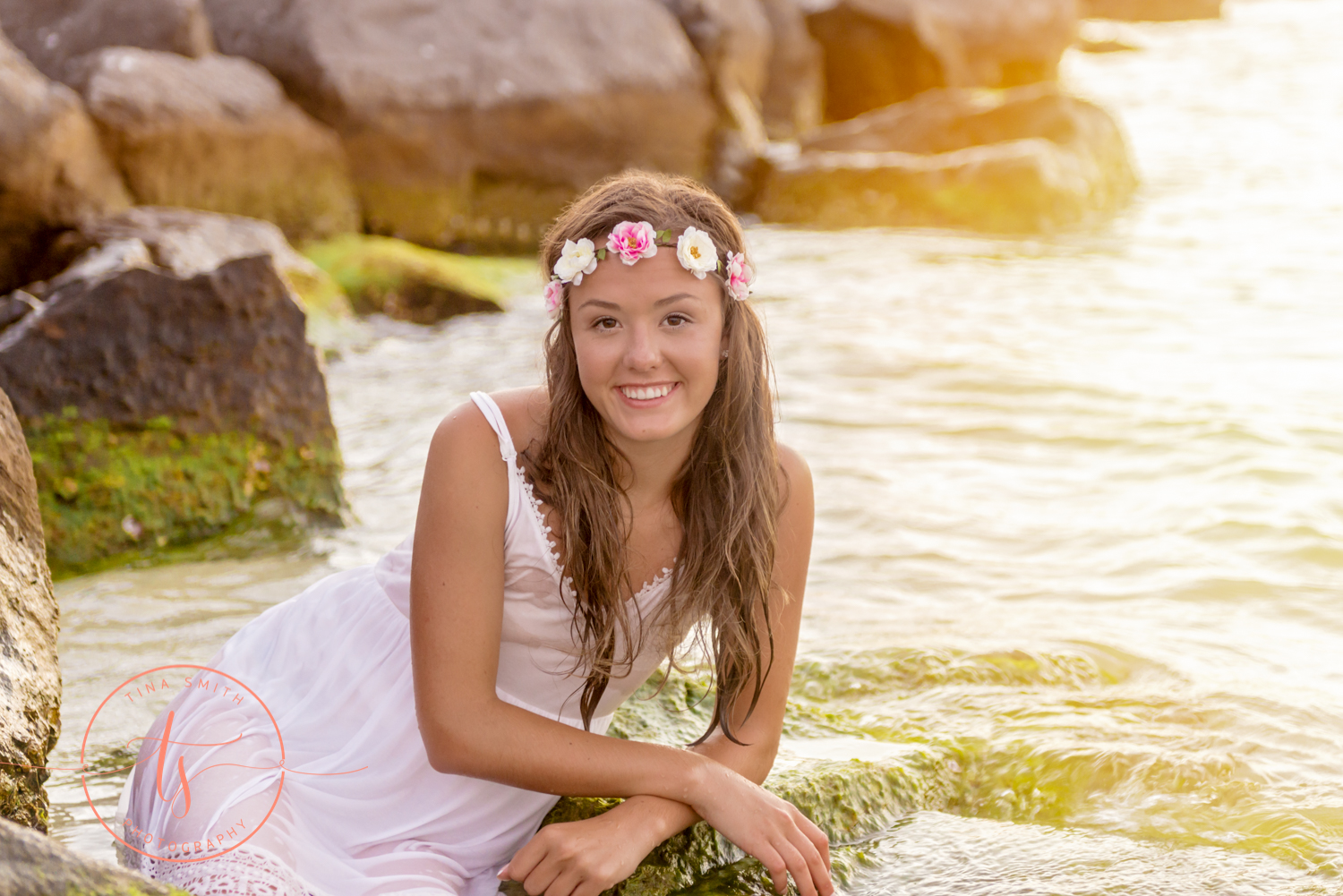 girl in white dress and flower headband lying in water at the beach in destin