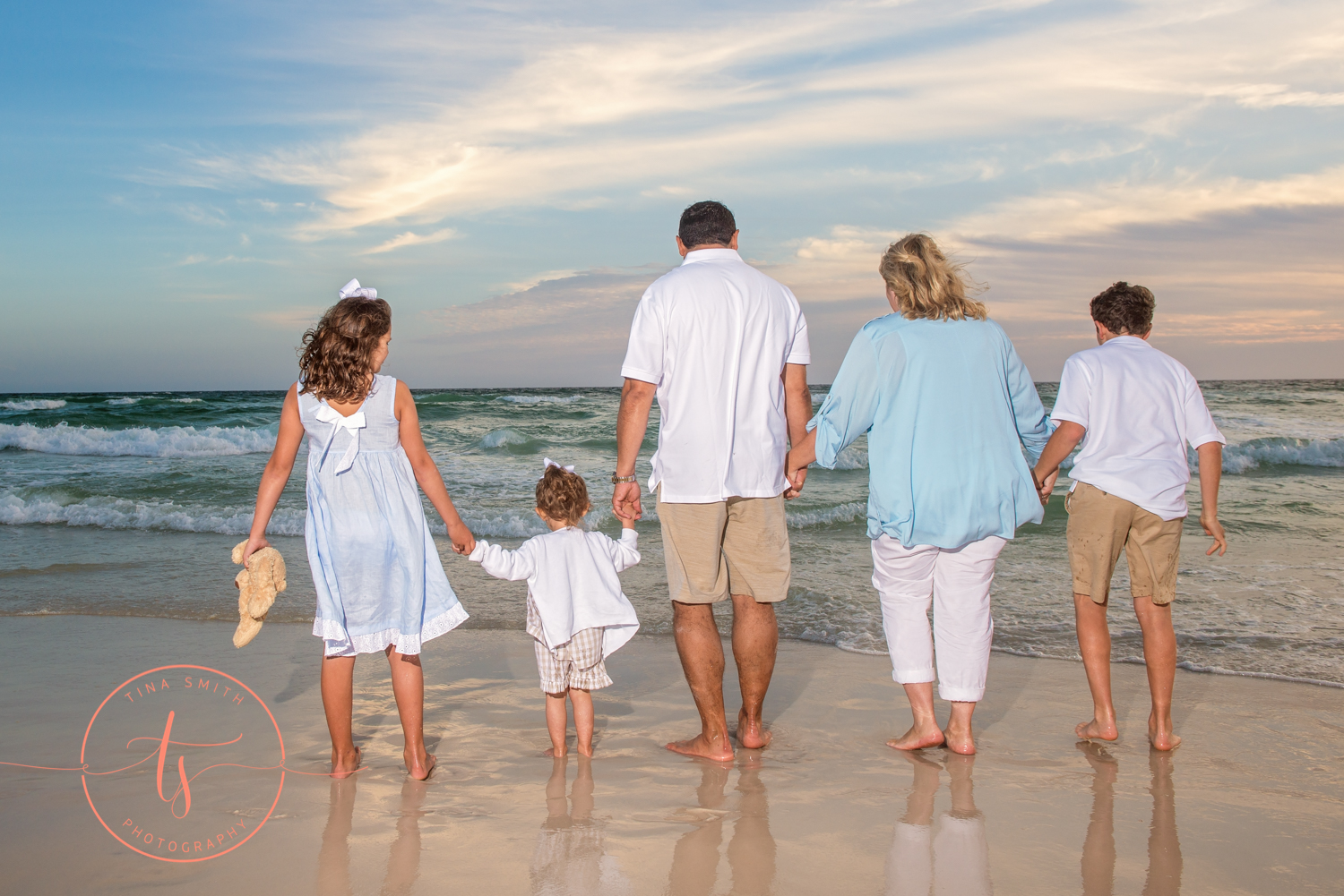 family walking down watersound beach holding hands