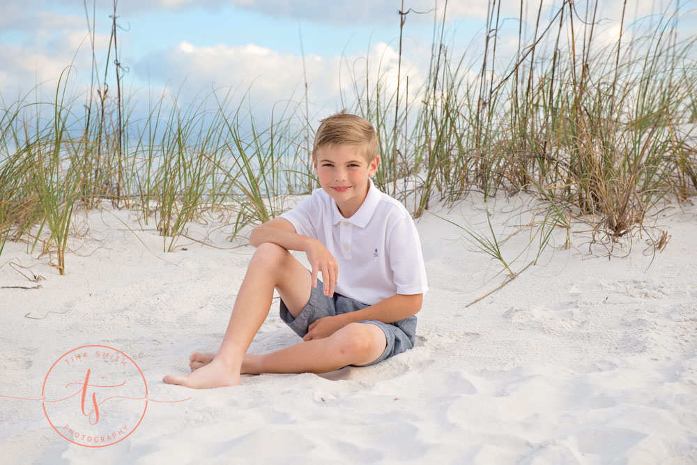 boy sitting in sand in dunes and sea oats