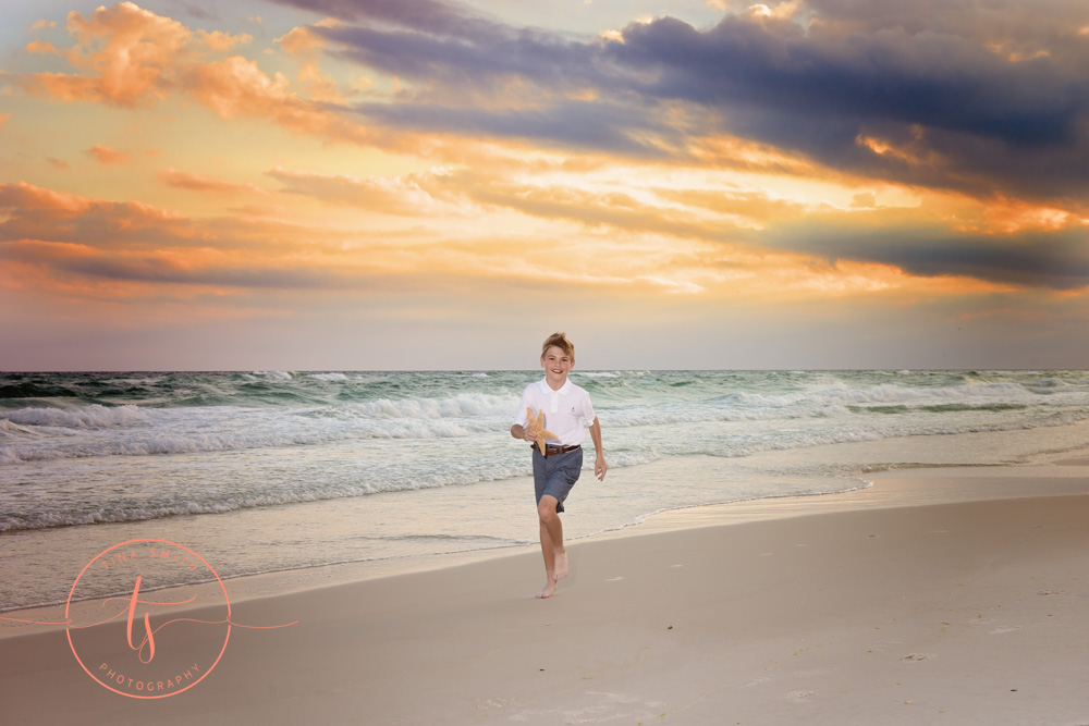 boy waling down beach at sunset