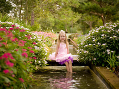 female child sitting by a fountain at a park in baytowne wharf