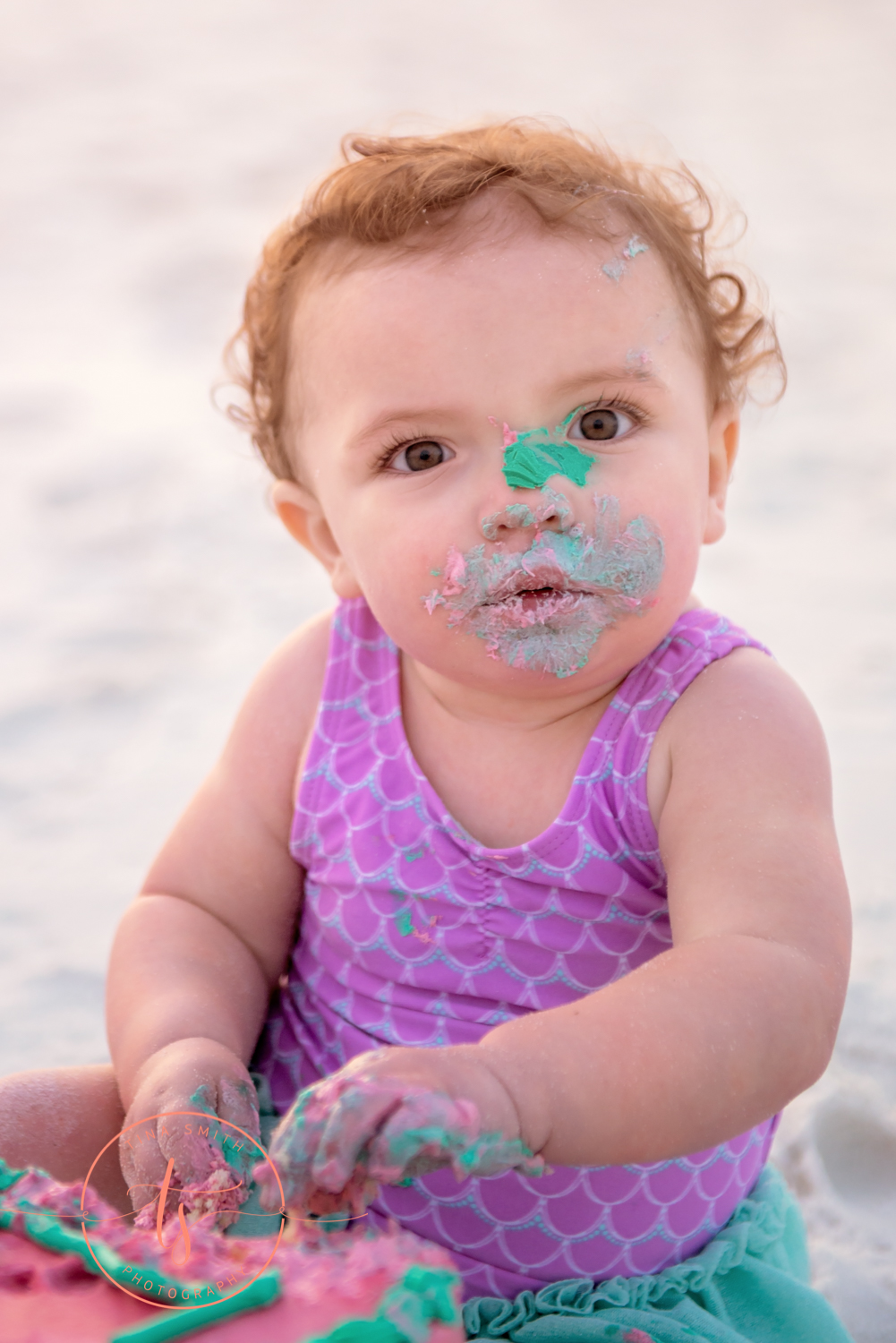 girl with cake icing on her face on the beach in destin