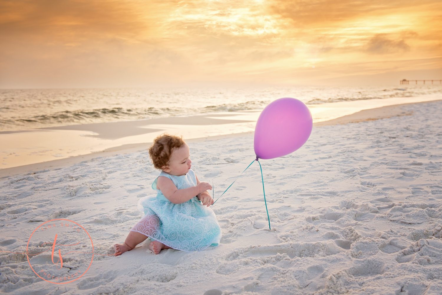 baby with balloon sitting on beach