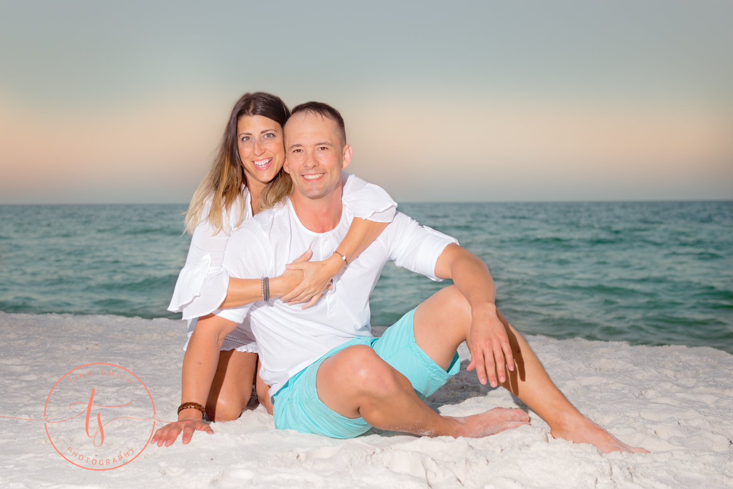 couple hugging on the beach smiling for photographer