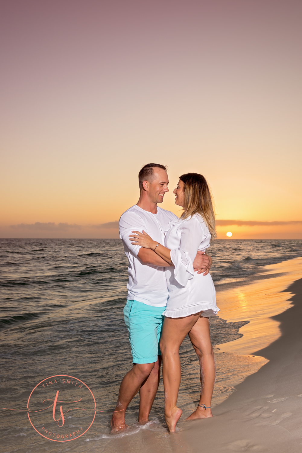 couple standing in water on beach in destin at sunset