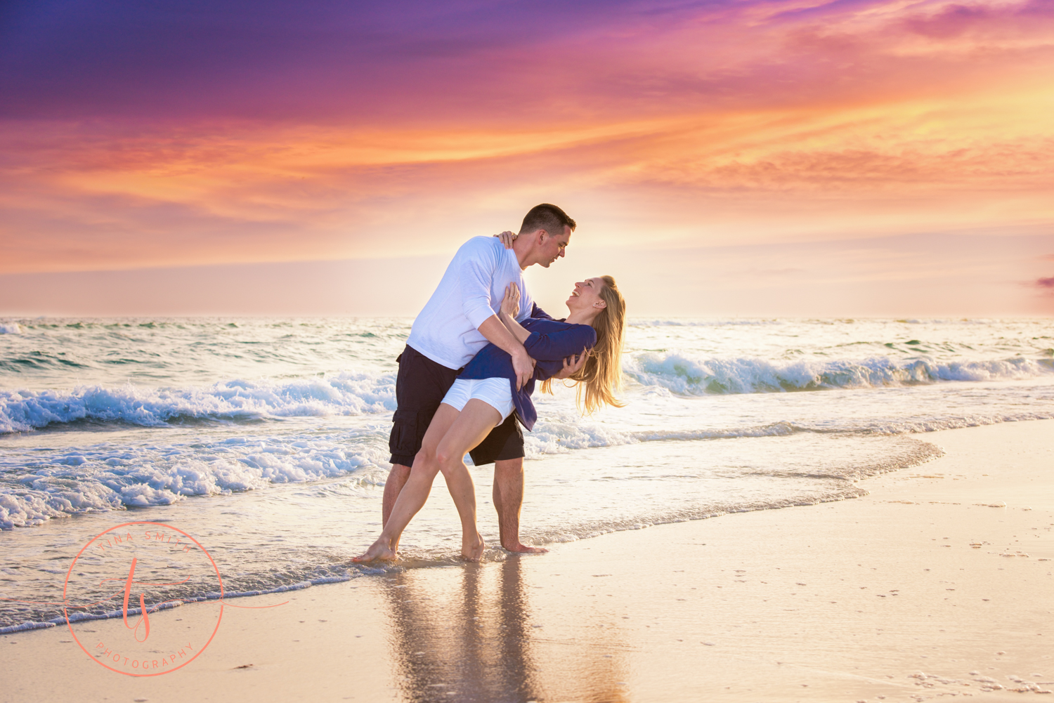 engaged couple dipping at sunset in water on beach in destin