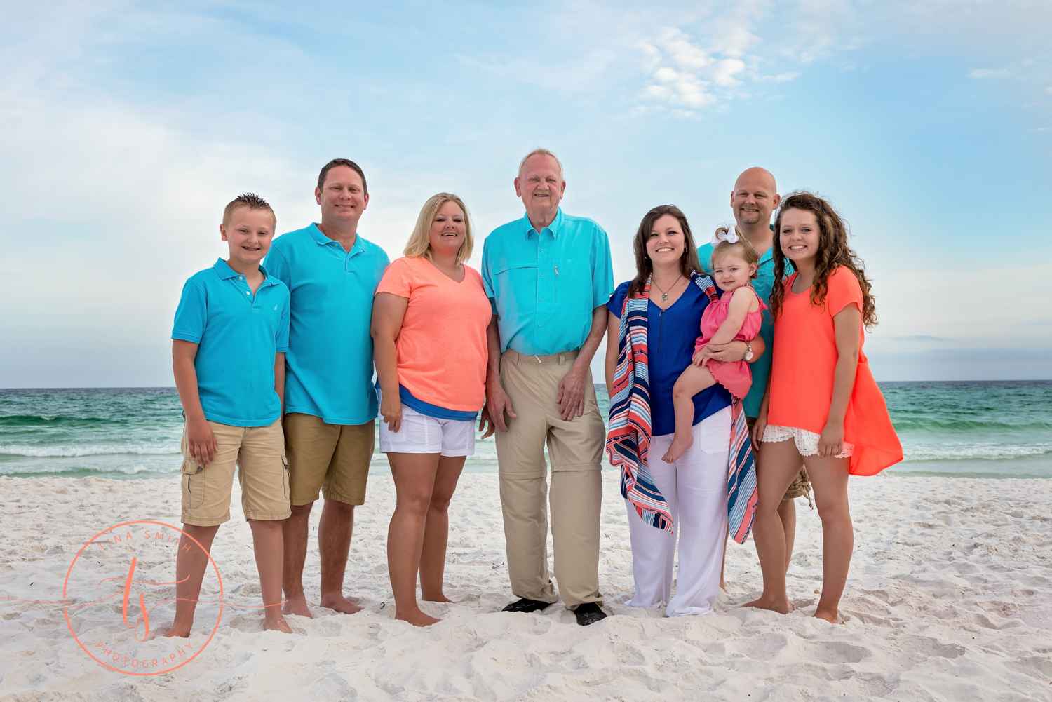 large family standing on beach smiling for photographer