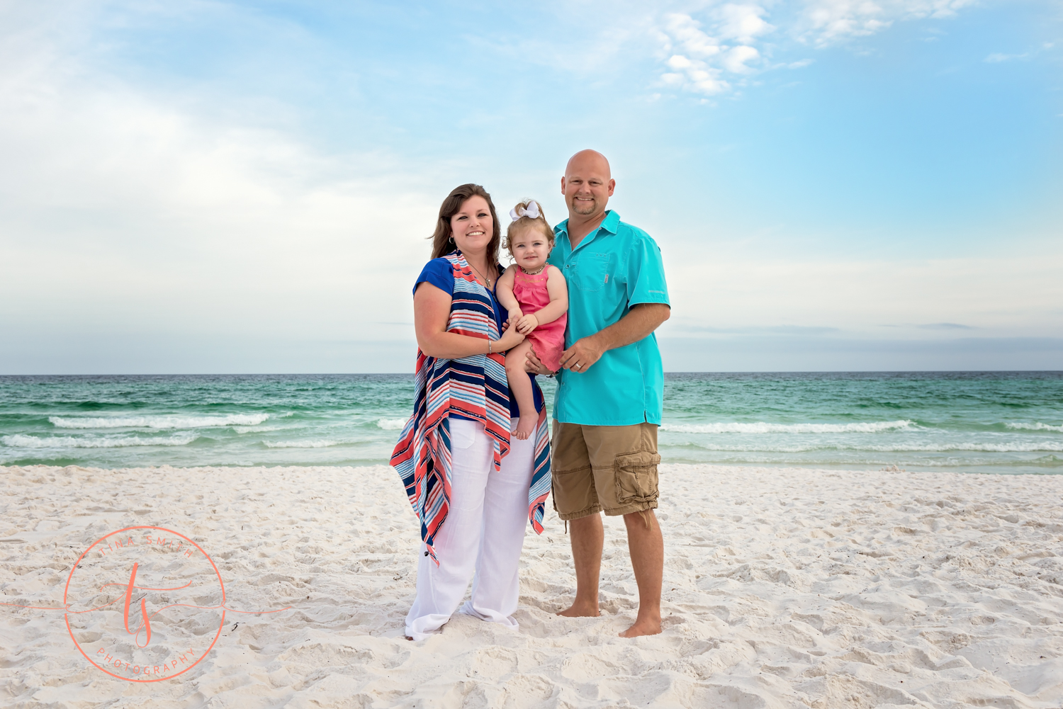 family of 3 standing on beach posing for portraits