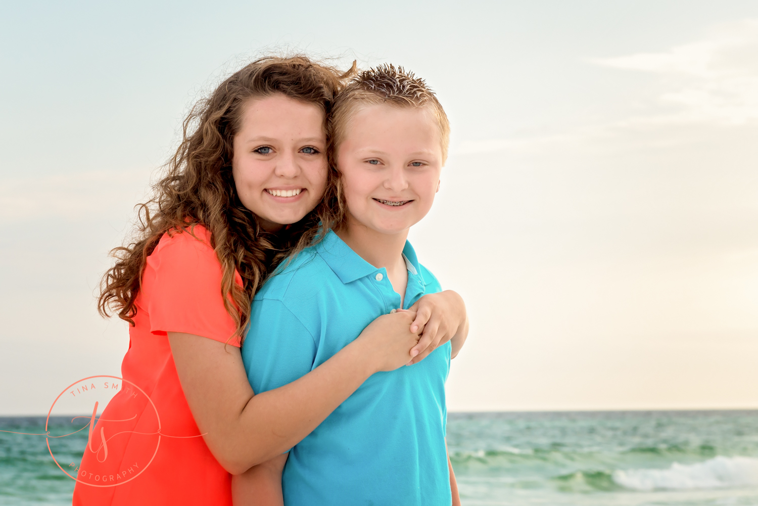 brothers and sister hugging and smiling on the beach for photography