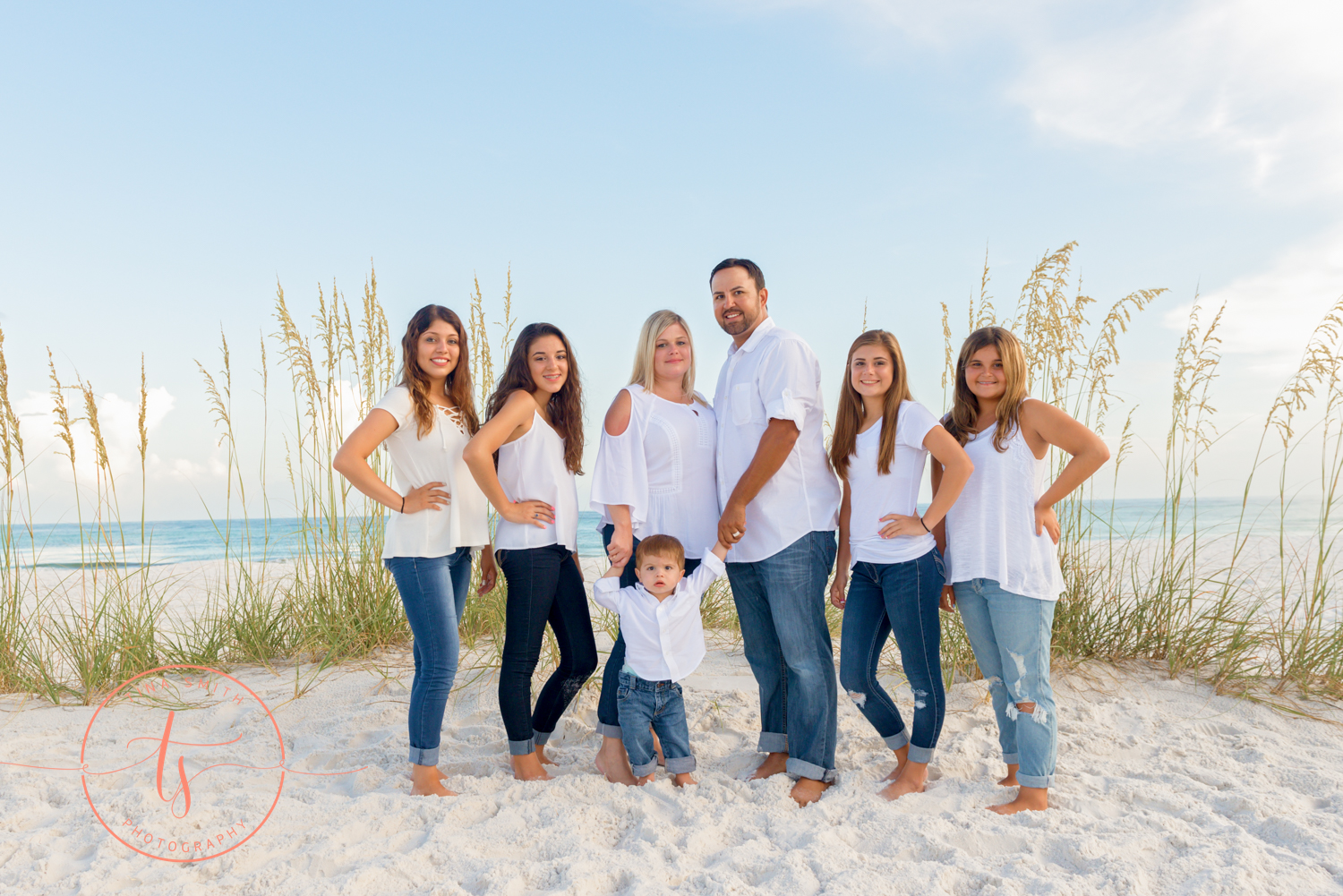 large family dressed in white posing on the beach for destin photographer