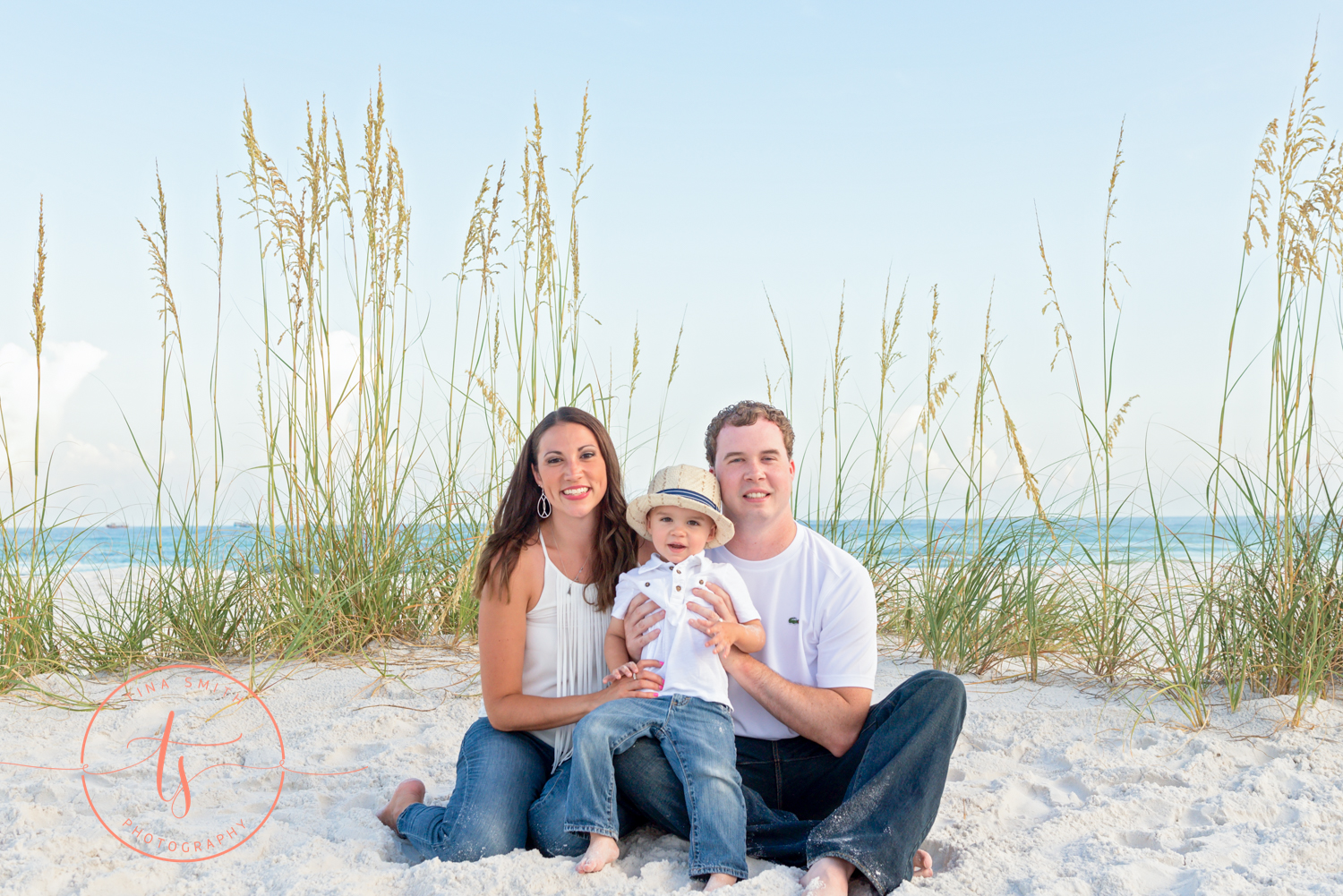 family of three sitting on the beach posing for destin family photographer