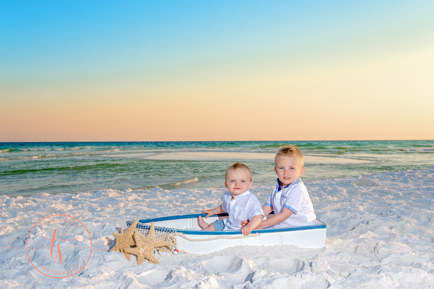 2 brothers sitting on beach in a boat at sunset