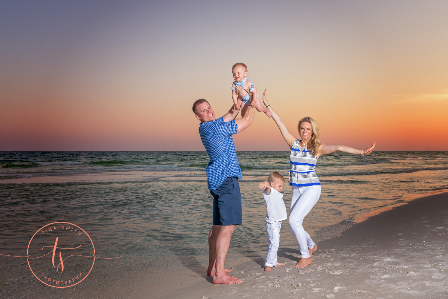 mom dad and 2 sons playing on the beach in destin at sunset