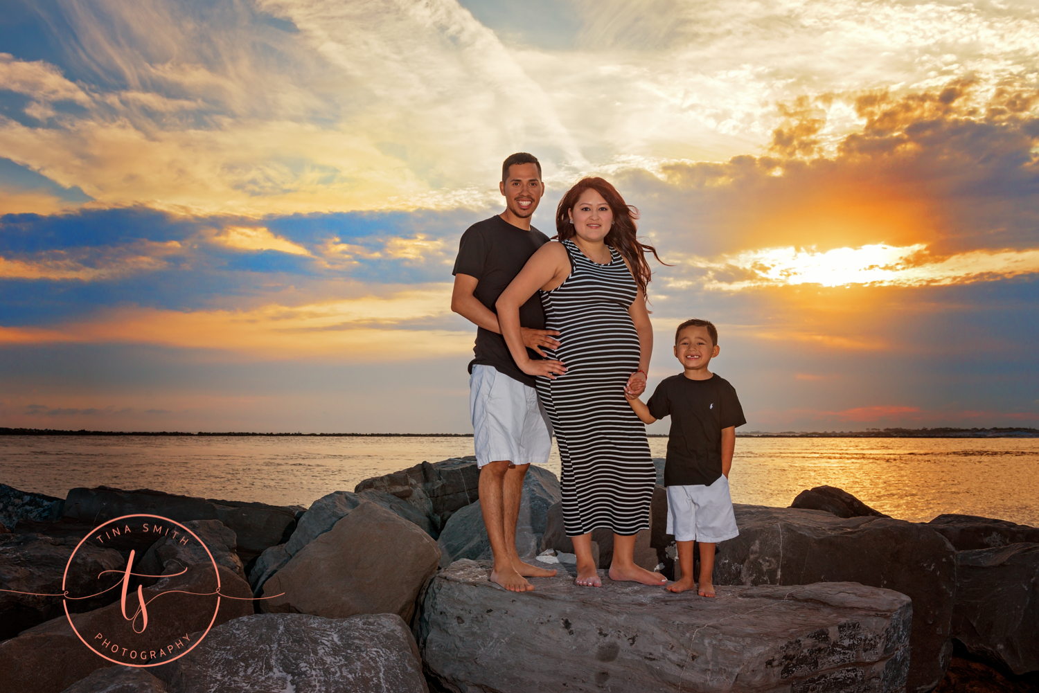 maternity family portraits on the rocks in destin at sunset