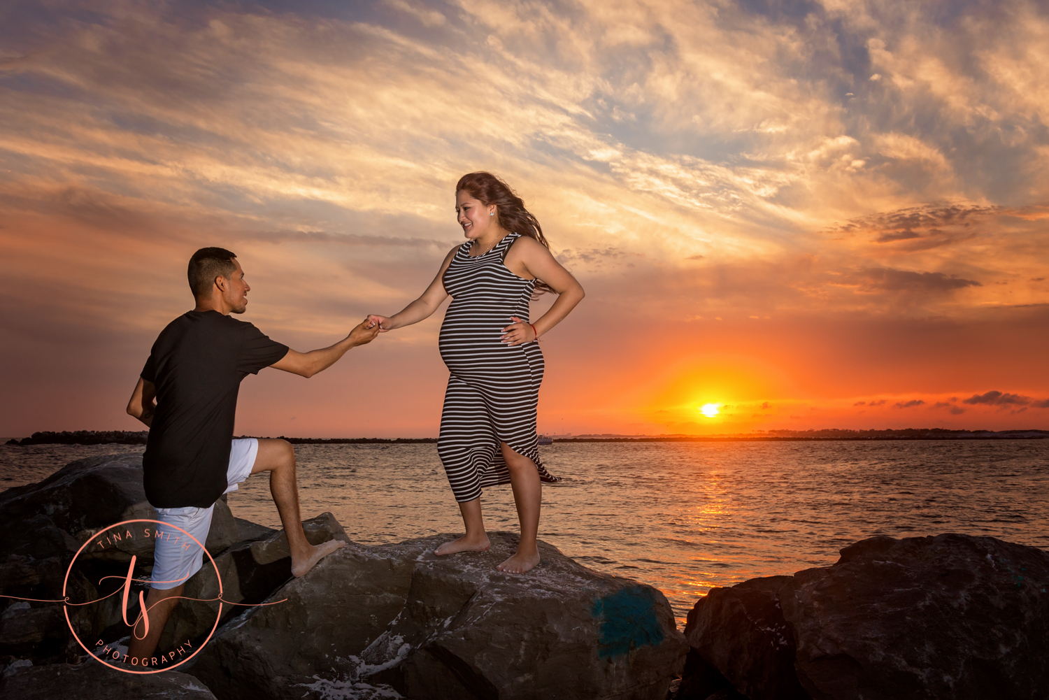 maternity couple posing on rocks at the beach in destin at sunset
