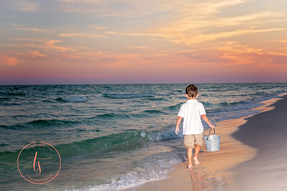 boy walking on beach in destin at sunset