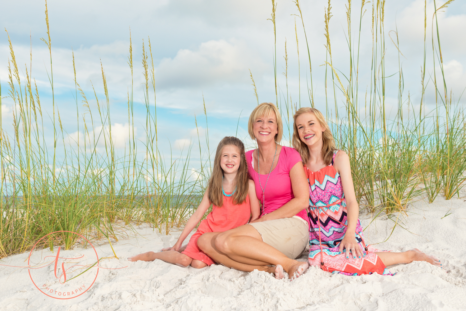 mom and daughters sitting on the beach posing for destin photographer