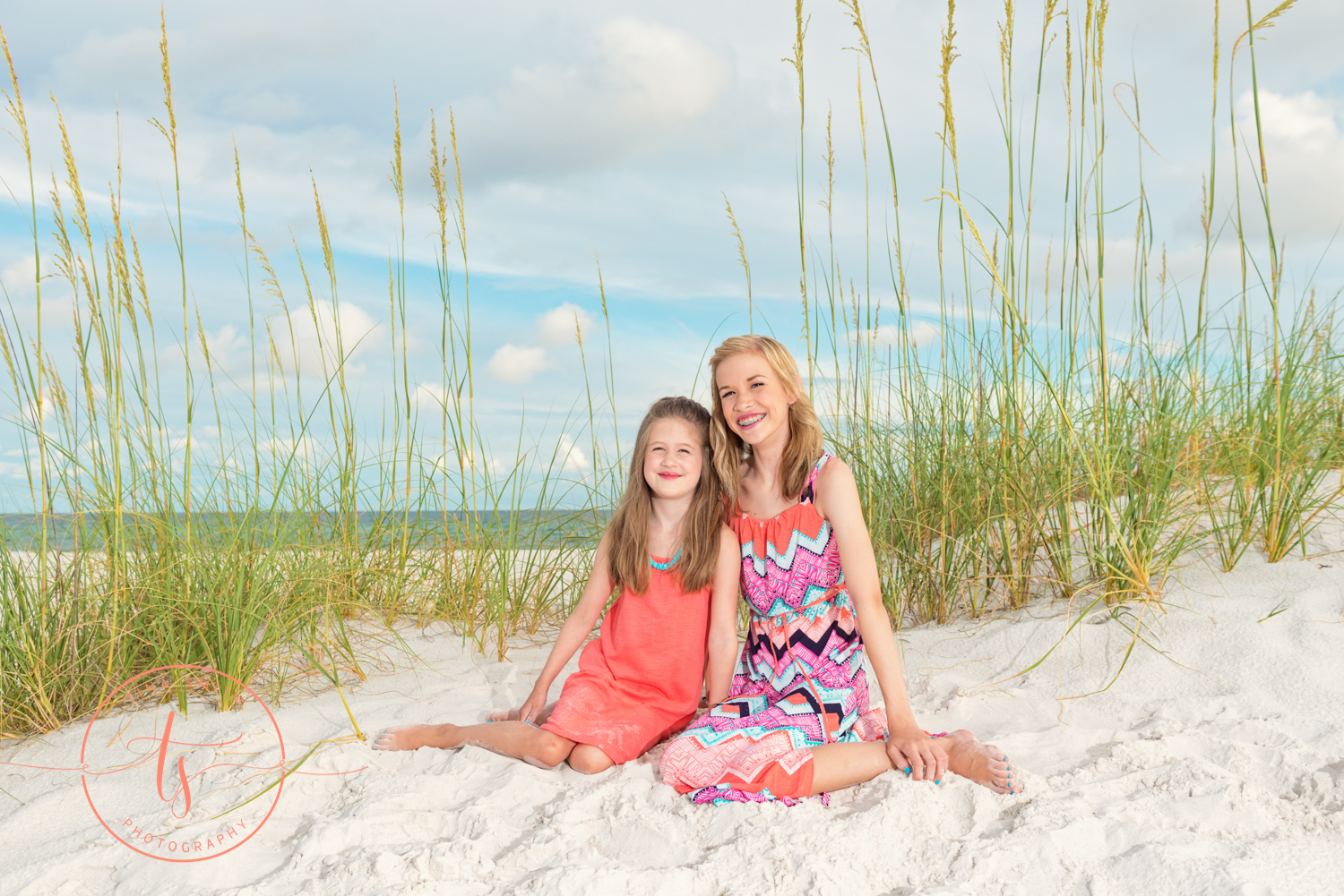 sisters sitting in front of sea oats posing for family portrait 