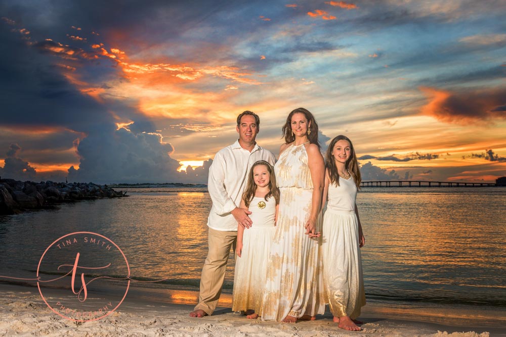 family dressed in formal wear standing on beach in destin at sunset