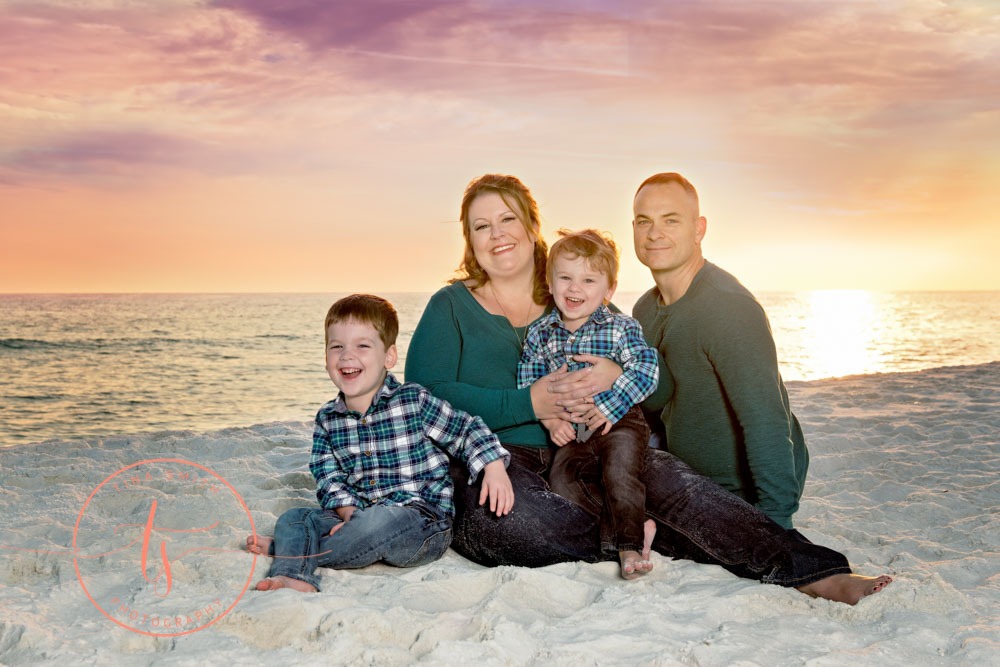 family sitting on the beach in destin smiling for photographer at sunset