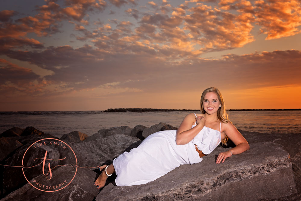 senior girl in white dress lying on jetty in destin