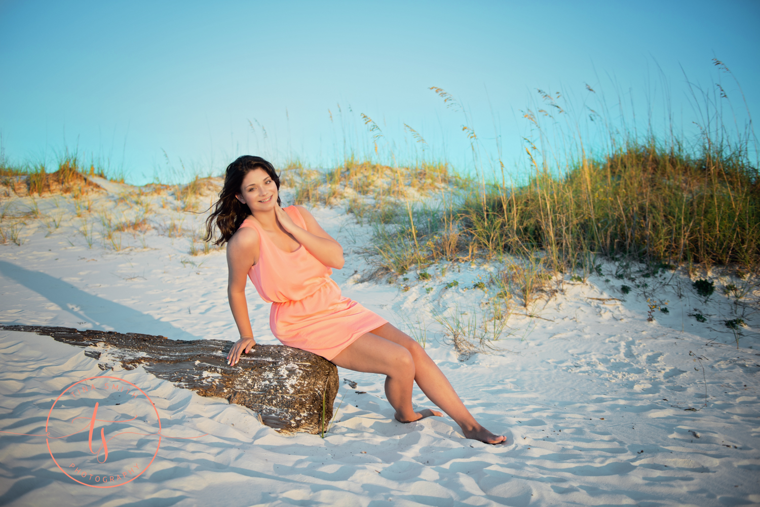 girl posing on log on beach in destin for senior portraits