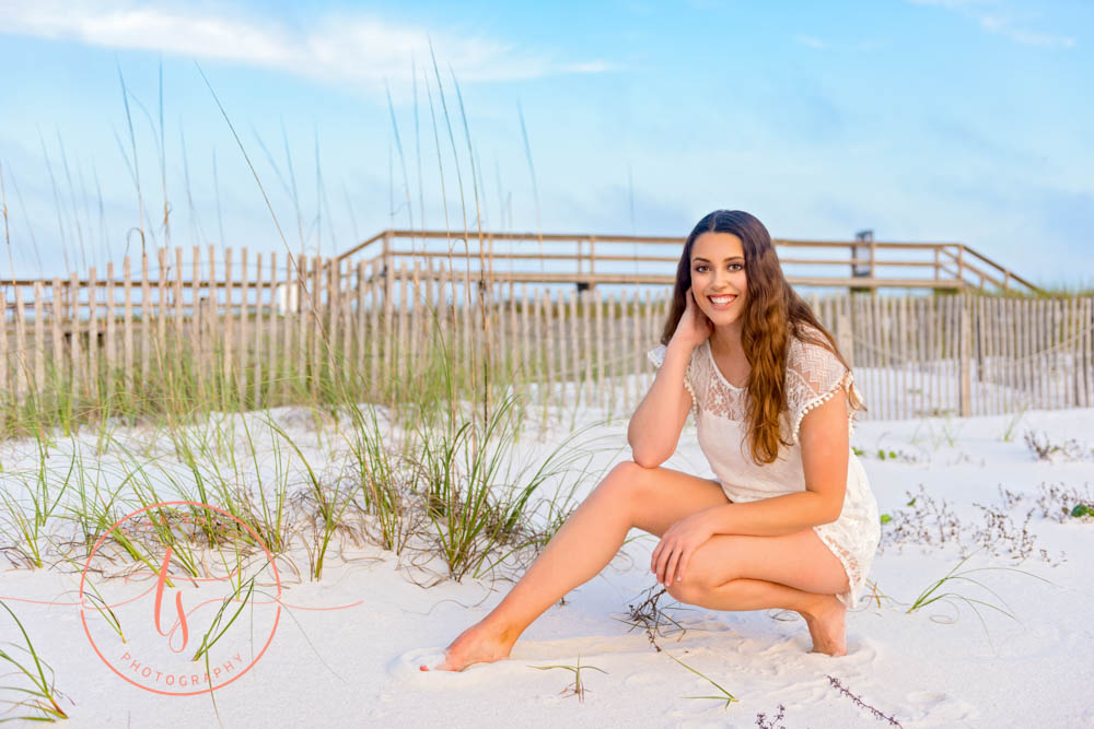 senior girl posing in front of wood fence on beach in destin