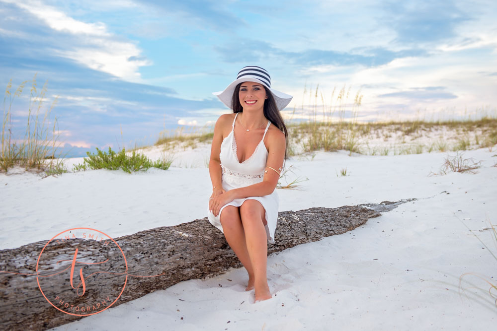 senior girl sitting on log on beach in destin