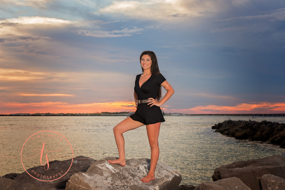 senior girl in black romper posing on rocks