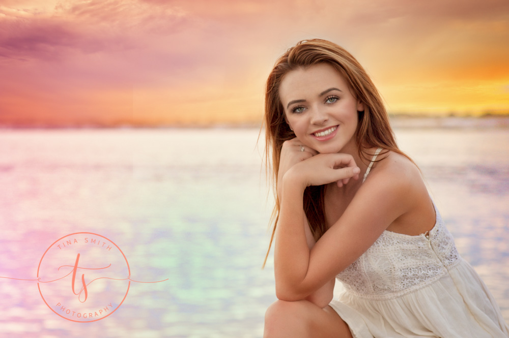 senior girl sitting on rock on destin beach