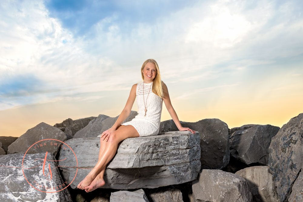 senior girl posing on jetties at sunset in destin