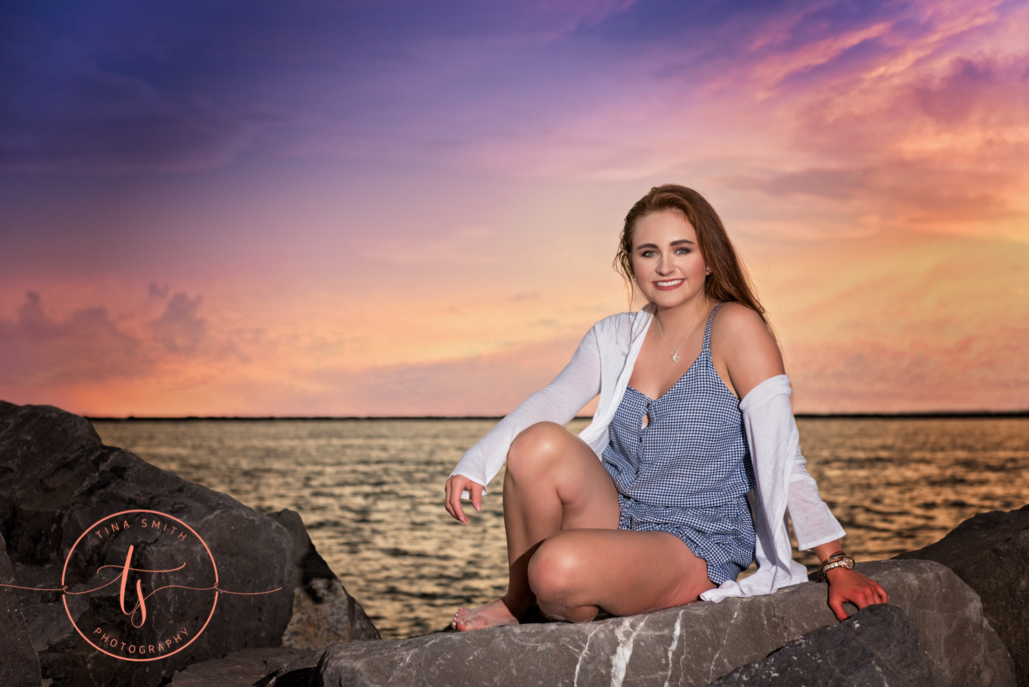 girl sitting on a rock in front of the water posing for pictures