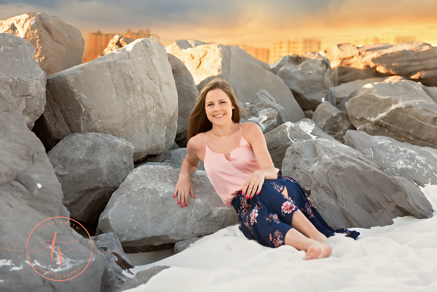 senior girl posing in front of rocks on the beach in destin