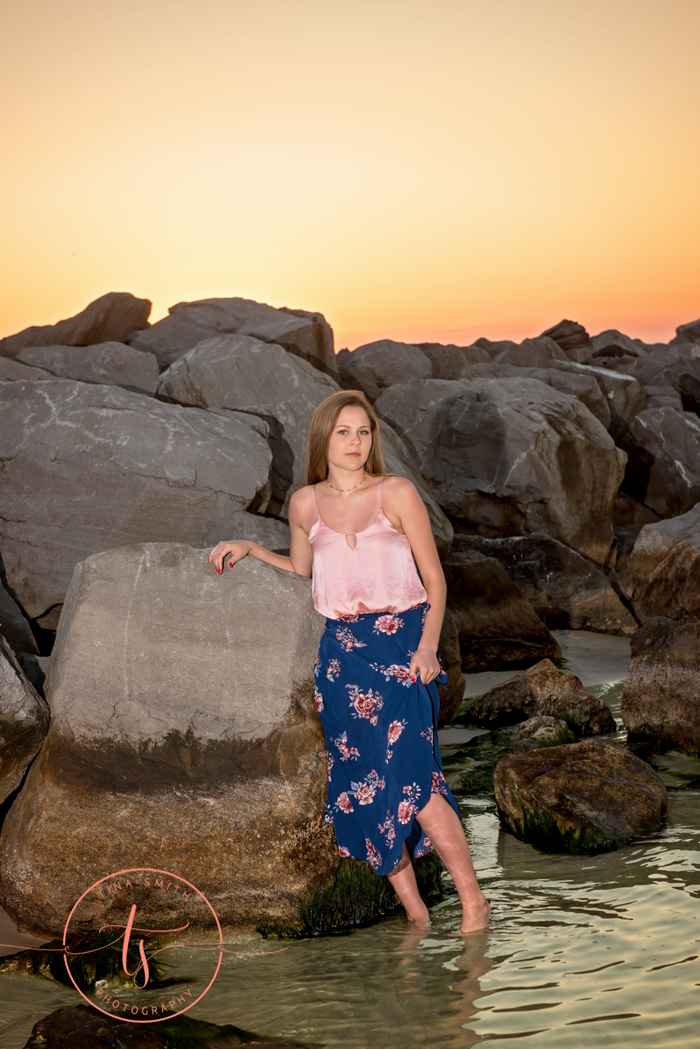 destin senior standing in water at sunset on beach