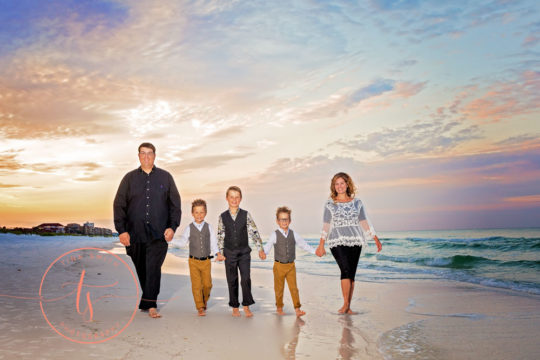 family walking down beach in destin at sunrise holding hands