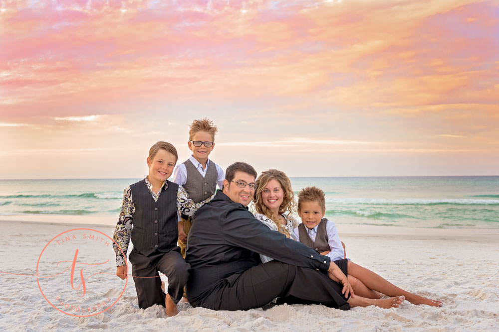 family sitting on beach at sunrise in destin